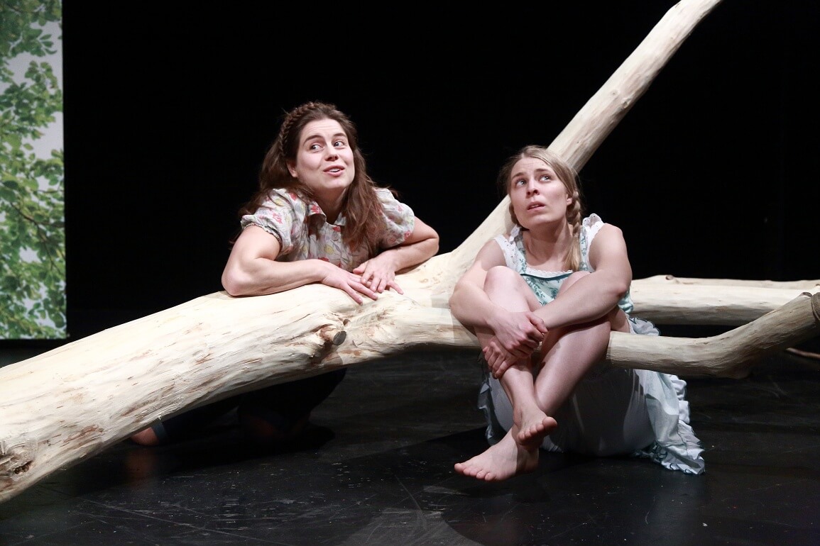 © Peter Schlipf Zwei Mädchen sitzen auf dem Boden, stützen sich auf einem Baumstamm ab und schauen in die Ferne