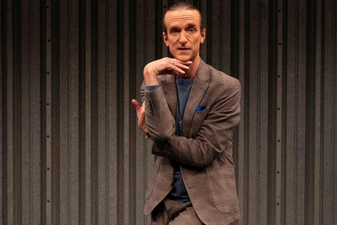 Ein Mann im einem Anzug, die Arme verknotet